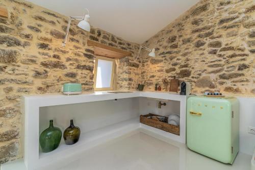 a kitchen with a refrigerator and a stone wall at Suites D´aldeia - Suite 16 in Mafra