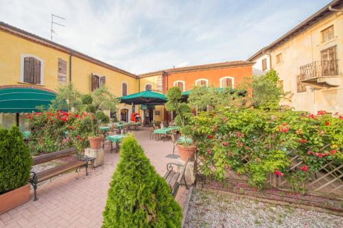 um pátio exterior com bancos, mesas e flores em Hotel Antichi Cortili em Dossobuono