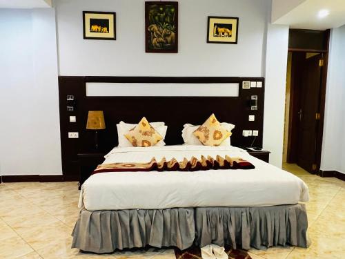 a bedroom with a large bed with white sheets and pillows at Green Mountain Hotel in Arusha