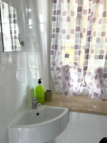 a bathroom with a sink and a window with curtains at Maison Bric in Millesimo