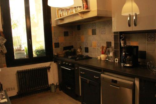 Il comprend une cuisine équipée d'une cuisinière. four supérieur à côté d'une fenêtre dans l'établissement Superbe appartement spacieux - Centre historique, à Montpellier
