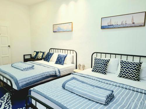 two beds with blue and white pillows in a room at 527 BeachHouse l 5 bedroom with swimming pool - 3min walk to the beach in Tanjung Bungah