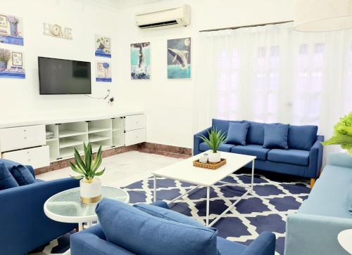 sala de estar con sofás azules y TV en 527 BeachHouse l 5 bedroom with swimming pool - 3min walk to the beach en Tanjung Bungah