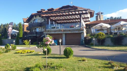 a large house with a garage in front of it at Family Hotel Eterno in Tsigov Chark