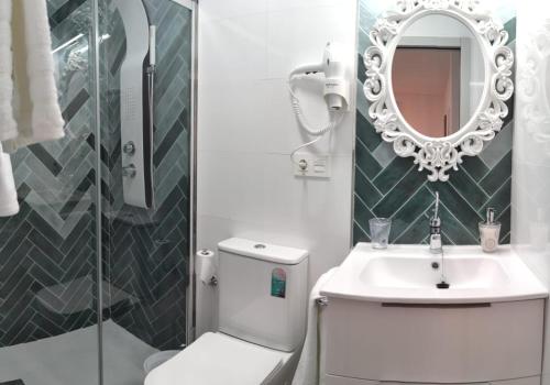 ein Badezimmer mit einem WC, einem Waschbecken und einem Spiegel in der Unterkunft Apartamentos Sol y Luna Conil in Conil de la Frontera