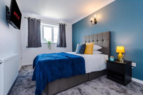 a bedroom with a bed with a blue wall at Family friendly 3-bed home with free parking on site in Lindley