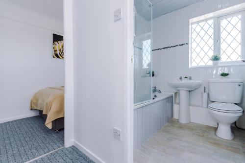 a white bathroom with a toilet and a sink at Family friendly 3-bed home with free parking on site in Lindley