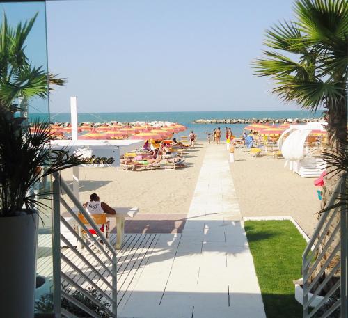 a beach with people sitting on the sand and umbrellas at Baldinini Hotel in Rimini