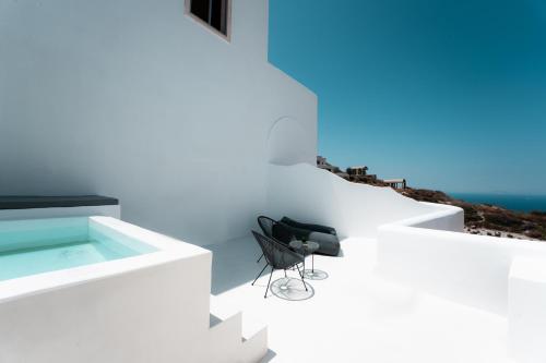 a black chair in a white room with the ocean in the background at Leon Luxury Suites in Imerovigli