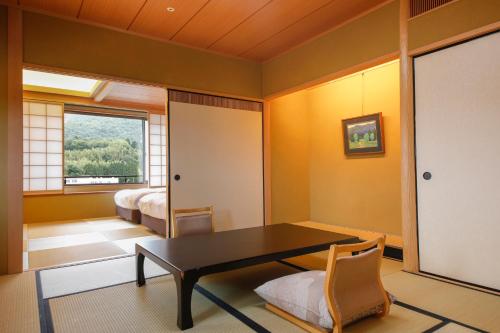 a living room with a table and a bedroom at Ginsuisou Choraku in Kobe