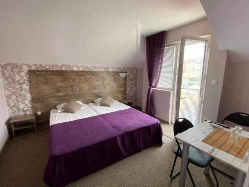 帕莫瑞的住宿－Guest House Taligarov，一间卧室配有一张紫色的床和一张桌子