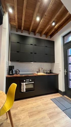 une cuisine avec des armoires noires, une table et une chaise jaune dans l'établissement La CORDERIE à 100 m de la plage Wifi, au Tréport