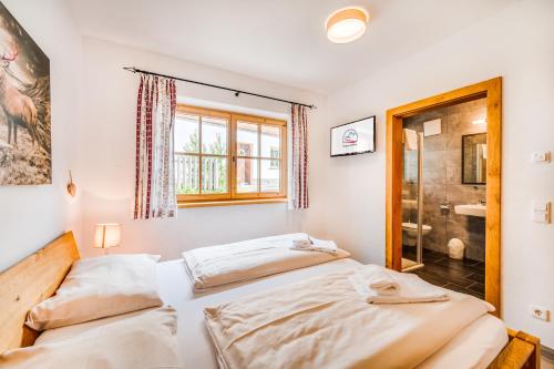 two beds in a room with a shower at Chaletdorf am Sonnenhang in Neukirchen am Großvenediger
