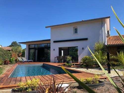 une villa avec une piscine en face d'une maison dans l'établissement La villa du golf, à Gujan-Mestras