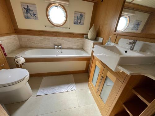 a bathroom with a tub and a toilet and a sink at Luxury boat - The Thistle Dream in Uxbridge