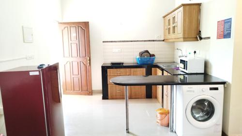 cocina con mesa y lavadora en Seacoast Retreat- Lovely 2 BHK apartment with pool, en Varca