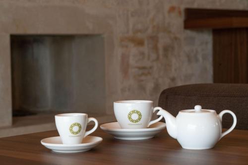 three white cups and saucers on a wooden table at DONNAPAOLA MODERN FARM in Altamura