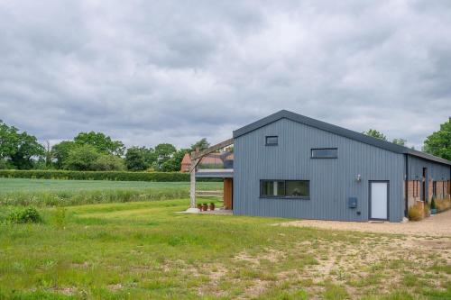 a gray barn with a garage in a field at Mandalore in Blyford