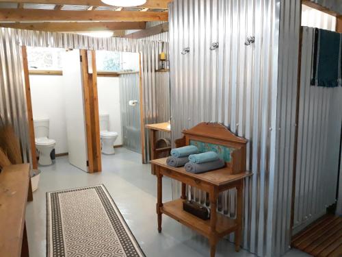 a bathroom with two toilets and a table with towels at Storms River Tin House in Stormsrivier
