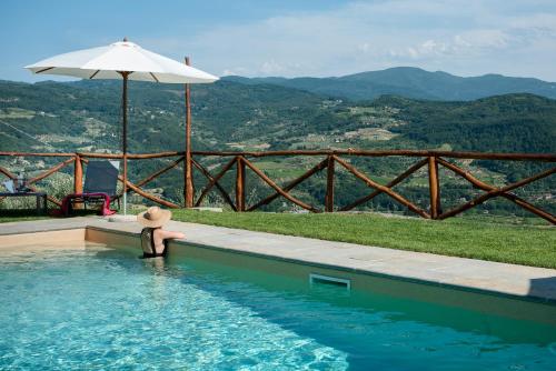 a person sitting in a swimming pool with an umbrella at Fienile in Pontassieve