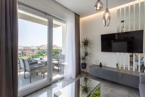 sala de estar con una gran puerta corredera de cristal y TV en Apartments Taratta 1, en Trogir