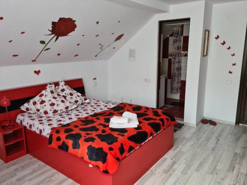 a bedroom with a red bed with a black and white comforter at Pensiunea Constanta in Bran