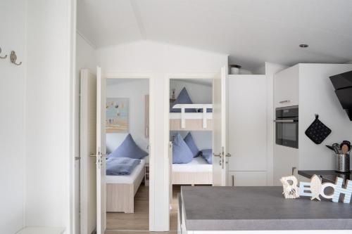 Cette chambre dispose de murs blancs et de lits superposés. dans l'établissement Ostseecamp Lübecker Bucht Meeresbrise, à Scharbeutz