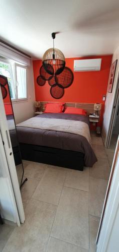 a bedroom with a bed and a red wall at Le Nid'Isle - Stationnement privé gratuit - Wi-Fi performant - Climatisation in LʼIsle-sur-la-Sorgue