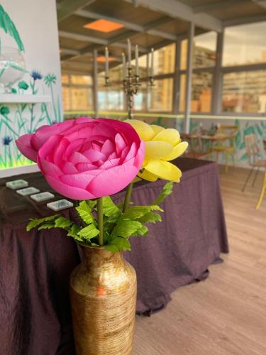 a vase with a pink rose and yellow flowers at Hotel Sireno Torremolinos - Adults Only, Ritual Friendly in Torremolinos