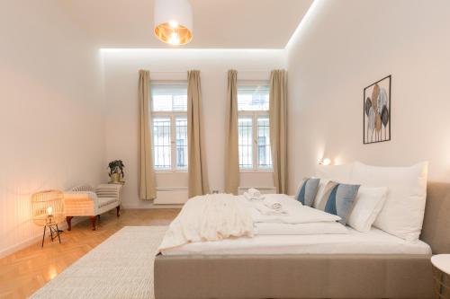 una camera bianca con un grande letto e due finestre di Space and Elegance in The Heart of Budapest a Budapest