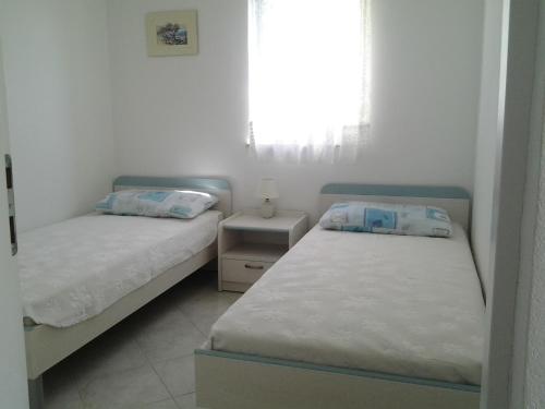two beds in a small room with a window at Apartments MiaMaja 2 in Novalja
