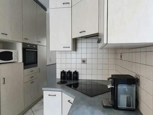 eine Küche mit weißen Schränken und einer Arbeitsplatte in der Unterkunft Appartement au n°1 centre d'Avranches in Avranches