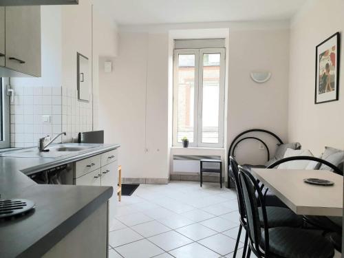 eine weiße Küche mit schwarzen Stühlen und einem Tisch in der Unterkunft Appartement au n°1 centre d'Avranches in Avranches
