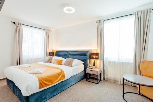 a bedroom with a large bed with a blue headboard and windows at Hotel Glaus in Banská Štiavnica