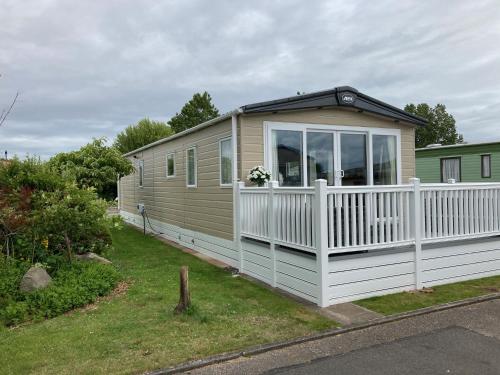 a tiny house with a white fence in a yard at Heywoods caravan holiday home in Morecambe