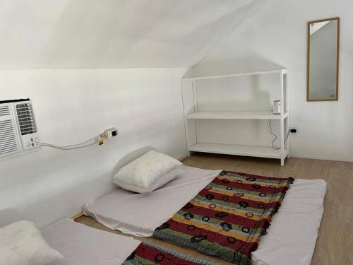 a white room with a bed and a mirror at Manzil Jina Laiya House Rental in San Juan