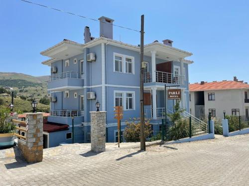 a large blue house with a sign in front of it at Parli Hotel in Gokceada Town