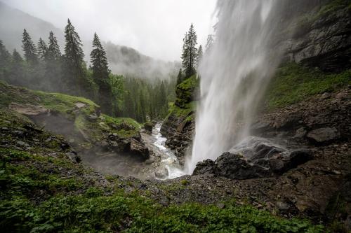 una cascada junto a una montaña con árboles en Dependance Dachsteinperle en Ramsau am Dachstein