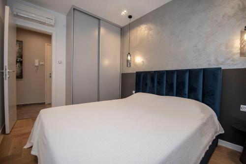 a bedroom with a white bed and a blue headboard at Apartment Aloha in Trebinje