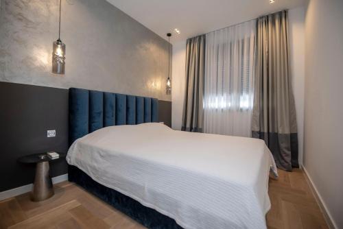 a bedroom with a white bed and a blue headboard at Apartment Aloha in Trebinje