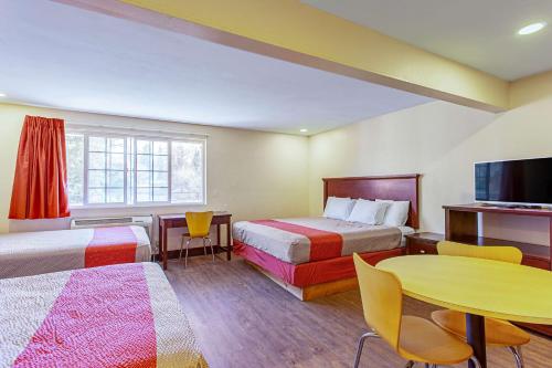 Habitación de hotel con 2 camas, mesa y TV. en Motel 6 Pendleton, OR - West en Pendleton