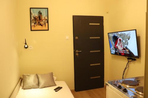 a room with a bed and a door with a tv at Little Zrin Rooms in Zagreb