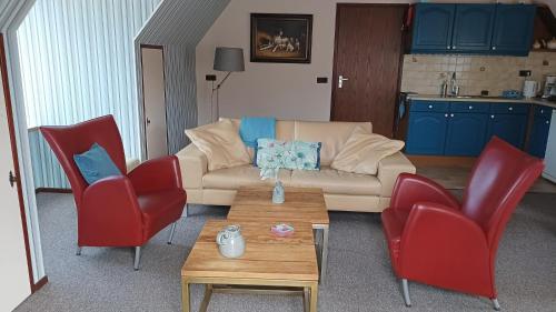 Vakantie appartement de Havezate في رودن: غرفة معيشة مع أريكة وكرسيين حمراء
