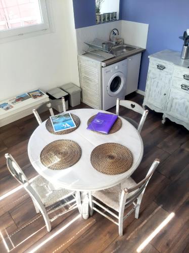 - une table blanche avec des chaises et un évier dans la cuisine dans l'établissement Le Provence - station balnéaire Les Sablettes, à La Seyne-sur-Mer