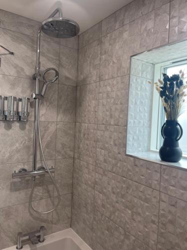 La salle de bains est pourvue d'une douche, d'un lavabo et d'un miroir. dans l'établissement Salisbury Suite - Modern 2 bedroom flat with parking in Menai Bridge, à Menai Bridge