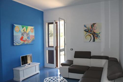 sala de estar con sofá y pared azul en blu appartament, en Trappeto
