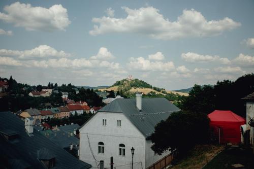 a white building with a hill in the background at Hotel Glaus in Banská Štiavnica