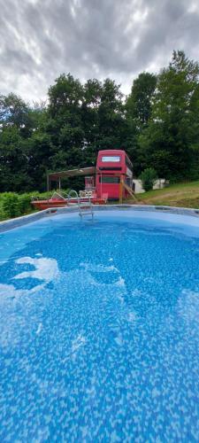 une grande piscine d'eau bleue devant une maison dans l'établissement insolite bus anglais le Buckinghambus, à Saint-Philbert-sur-Risle