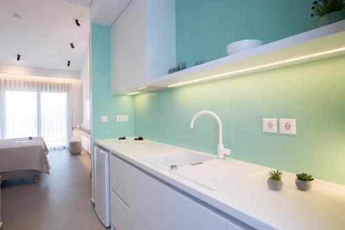 cocina con fregadero blanco y pared azul en Elianthi Luxury Apartments, en Nikiana