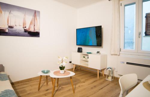 a white living room with a tv and a table at Meraki House in Alghero